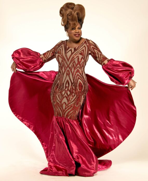 Drag performer in an elegant red satin and sequined gown with sculpted hair for Palace South Beach in Miami Beach