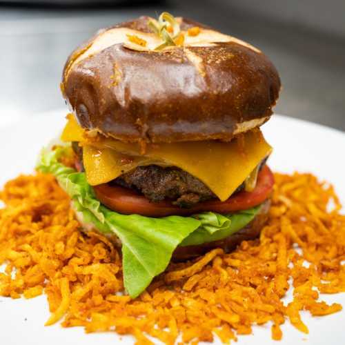 Cuban Frita beef burger with double cheese, tomato, lettuce on a brioche bun, served with fries at Palace South Beach