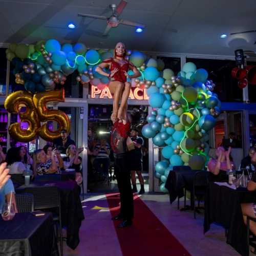 Oscar lifting Tiffany in an aerial pose, both dressed in red, at Palace South Beach