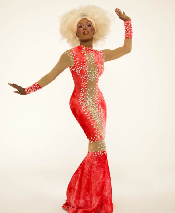 Drag performer in a red rhinestone gown with voluminous blonde hair for Palace South Beach in Miami Beach