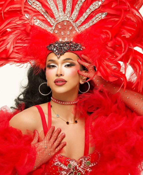 Drag performer wearing an elaborate red feather and rhinestone headdress for Palace South Beach in Miami Beach