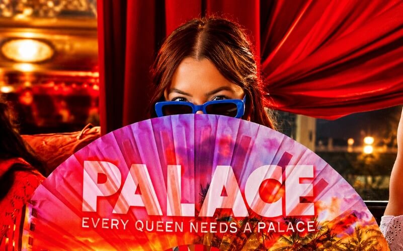 Woman peeking over a "Palace" fan at Palace South Beach's drag brunch on Ocean Drive, Miami